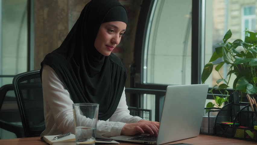 Muslim islamic woman in hijab Arabian businesswoman drink glass water at workplace office female girl business lady student freelancer drinking thirst refresh break work laptop healthy wellness smile