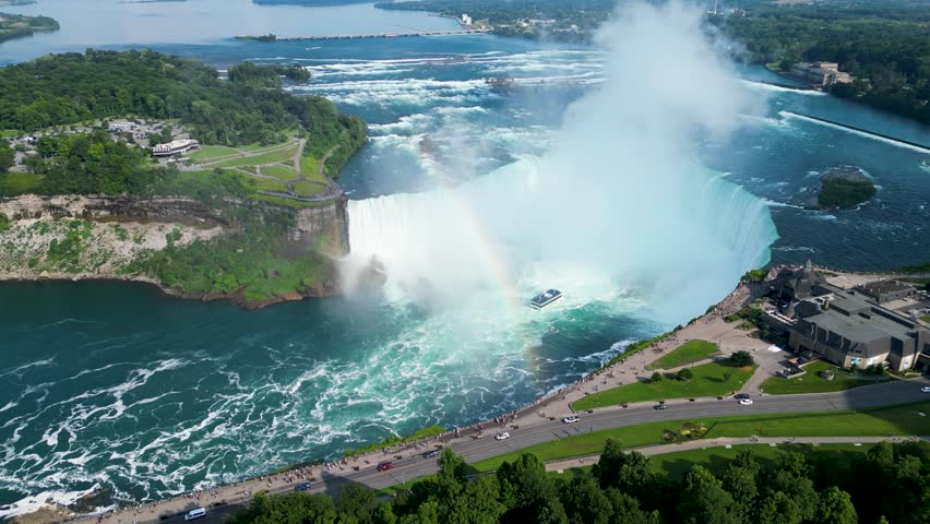 Cinematic drone shot of Horseshoe waterfall with rainbow at Niagara Falls with boat inside in Ontario (Canada) 