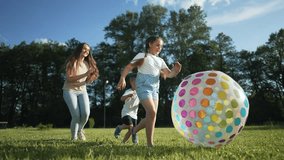 Happy family playing on grass with ball. Mother and daughter enjoy sunny day outdoors. Colorful ball and laughter fill air. Family bonding playing ball together. Joyful family moments playing on grass - Powered by Shutterstock - Get 15% off with code: PIKWIZARD15