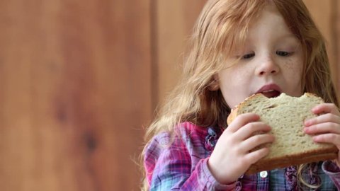 Redheaded girl eating peanut butter and jelly sandwich