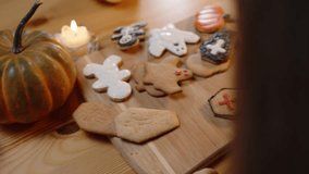 A Woman Decorates a Coffin-Shaped Cookie with a Cross, Applying Icing from a Piping Bag. Homemade Sweets for Halloween. - Powered by Shutterstock - Get 15% off with code: PIKWIZARD15