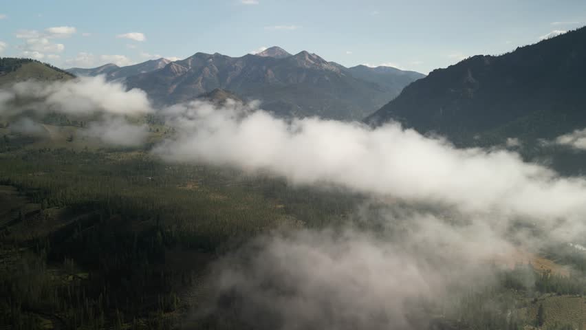 Aerial above low clouds in Sawtooth Mountains in Stanley Idaho in summer in early morning
