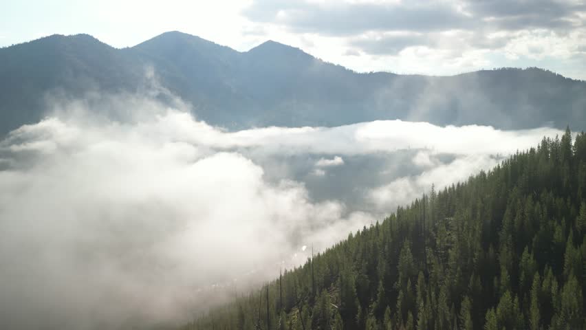 Aerial of low clouds in Sawtooth Mountains near Stanley Idaho on early summer morning