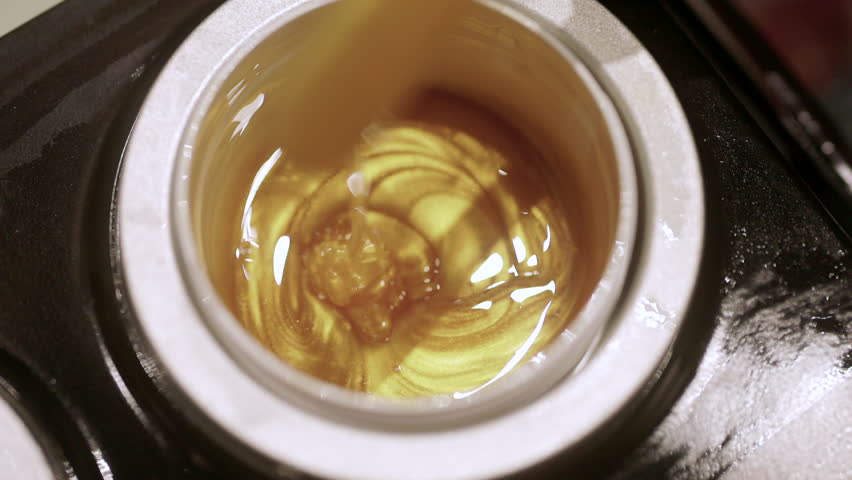 Brightly colored wax beads are heated and stirred evenly with a wooden stick. Wax beads for hair removal.