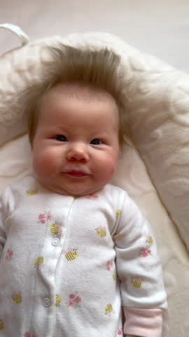 Cute Caucasian newborn baby girl smiling. First smiles concept. Infant development, baby milestones. Healthy, happy baby
