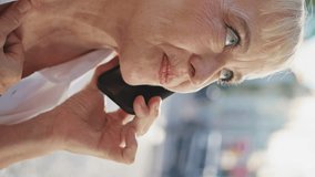 Smiling elderly woman calling mobile phone on sunny street close up. Portrait of elegant beautiful pensioner talking on smartphone outdoors vertical video. Happy old lady enjoy phone communication. - Powered by Shutterstock - Get 15% off with code: PIKWIZARD15
