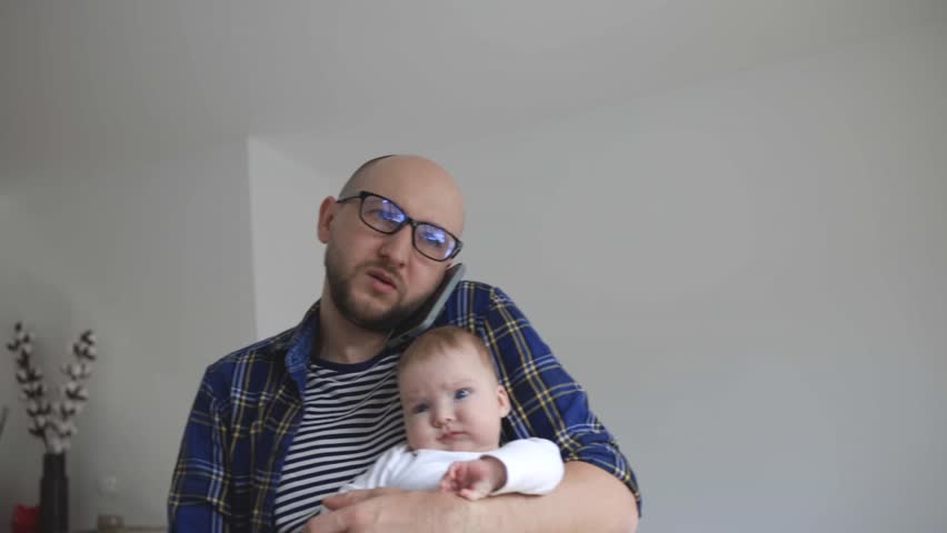 man with a child in his hands tries to work from home.