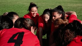A joyful female soccer team in red jerseys huddles together, showing enthusiasm and team spirit before a game. Excited Female Soccer Team in Pre-Game Huddle - Powered by Shutterstock - Get 15% off with code: PIKWIZARD15