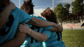 Female rugby players in blue jerseys huddled together, showcasing unity and team spirit before a game. Female Rugby Team Huddled Together in Unity - Powered by Shutterstock - Get 15% off with code: PIKWIZARD15