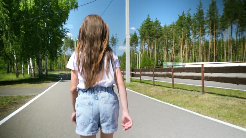 child girl runs along road park. child loves run around laughing merrily. running child from back. little running kid. playing child forest. summer nature park outdoor