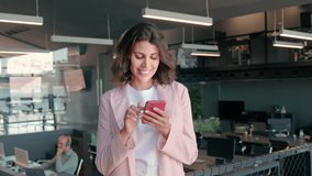 Young Indian woman manager using cell phone mobile AI app for call, business communication, trading. Focused Latin Hispanic female businesswoman holding smartphone for online work, standing in office - Powered by Shutterstock - Get 15% off with code: PIKWIZARD15