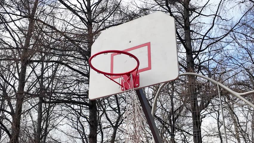 Outdoor basketball basket with torn net wobbly in the wind