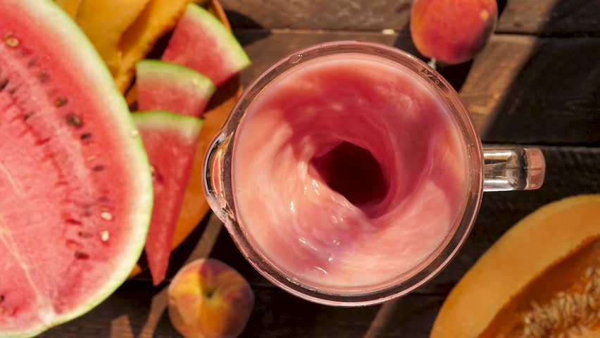 Top view of watermelon and melon mixed using blender in slow motion. Cold refreshing drink with watermelon melon flavor red color shaken using blender. Summer cocktail menu