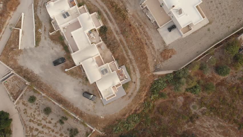Typical white Greek house, Architecture on the Cyclades, in Kamari, Santorini Island, Greece. Aegean Sea, Mediterranean. Aerial panorama drone view of area with houses and field
