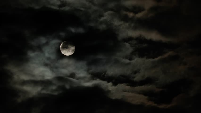 Full moon in the night sky with flying black clouds. Cloudy dark sky and moonlight in spooky feeling like thriller and horror films. Real video recording