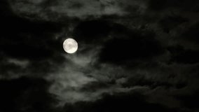 Full moon in the night sky with flying black clouds. Cloudy dark sky and moonlight in spooky feeling like thriller and horror films. Real video recording - Powered by Shutterstock - Get 15% off with code: PIKWIZARD15