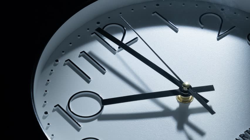 A timelapse video of moving wall clock hand on a dark background