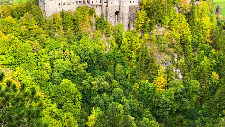 Neuschwanstein castle on Alps background in vicinity of Munich, Bavaria, Germany, Europe. Autumn landscape with castle and lake in mountains covered with spruce forest. High quality 4k footage