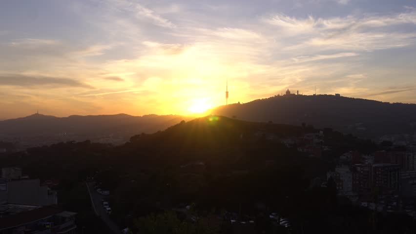 A landcape sunset view of countryside mountains over fields  and cars