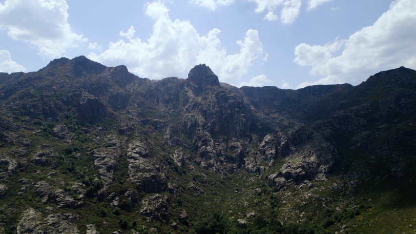 A landscape footage of green cliffs range valley with blue cloudy sky