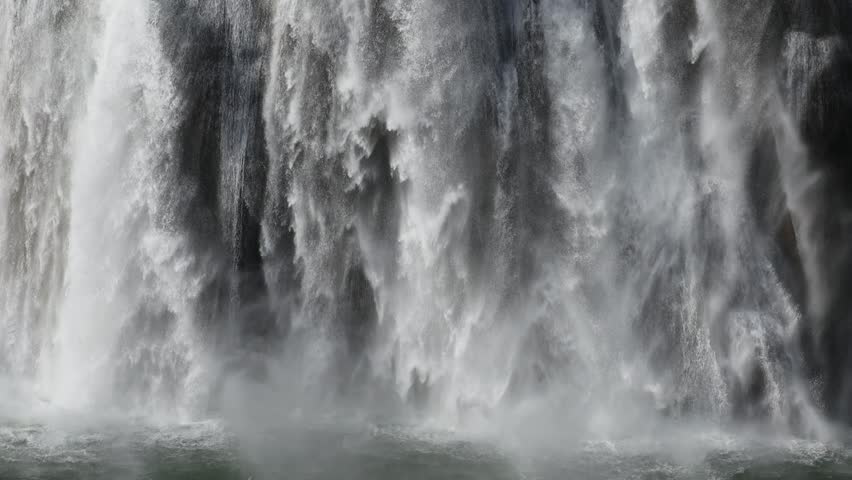 A landscape scene of a heavy waterfall flowing with foam on the river