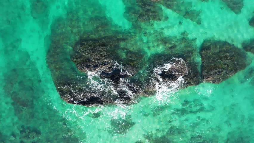 An aerial top view video of sea waves crashing on the rocky shore
