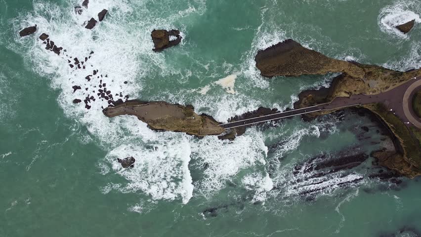 An aerial top view video of sea waves crashing on the shore covered with buildings