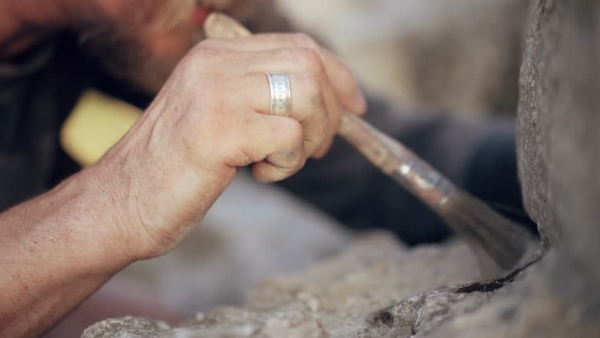 Archaeologist working with a brush at an excavation site