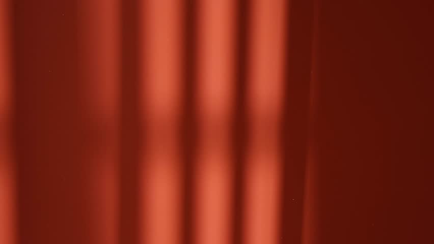 Black vertical lines shadow moving on sunny red wall