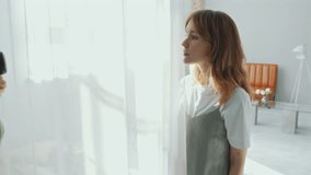 Young beautiful blonde woman standing beside sheer curtain and posing, male photographer taking pictures with camera during photo shoot in modern studio - Powered by Shutterstock - Get 15% off with code: PIKWIZARD15