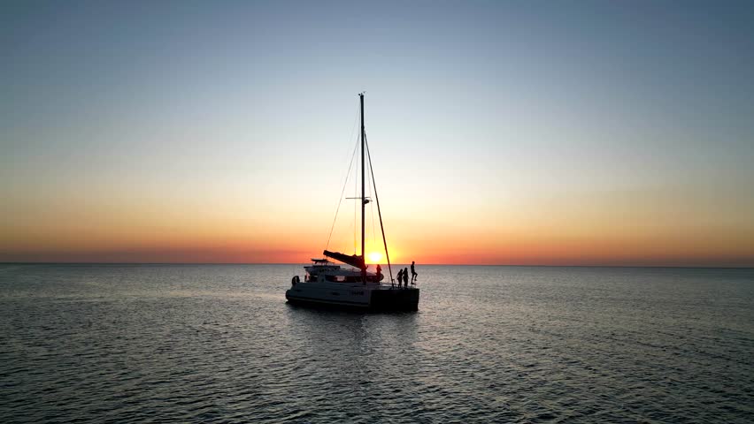 A beautiful sunset scene of a sailing boat in the sea under colorful dusk sky