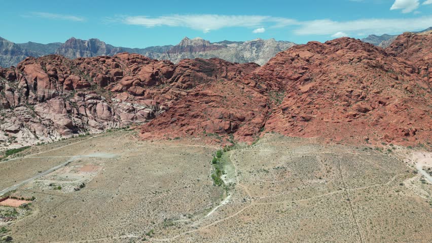 An aerial video of the dry high rocky red mountains on a sunny day