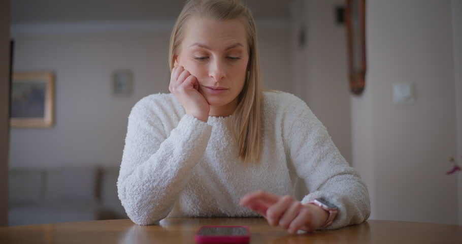 A woman looking at the phone and anxiously waiting for an important call