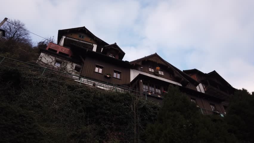 DOLLY SHOT - Rustic houses built at the foot of the Alpine Mountains in Hallstatt. Real stone fragment in the wall of a wood residential building. Austria.
