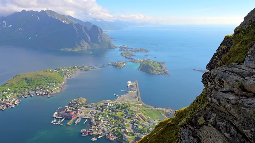 Immerse yourself in the tranquil beauty of a quaint town nestled amidst a serene lake and towering mountains. A breathtaking display of natures harmony, Reinebringen Lofoten Norway