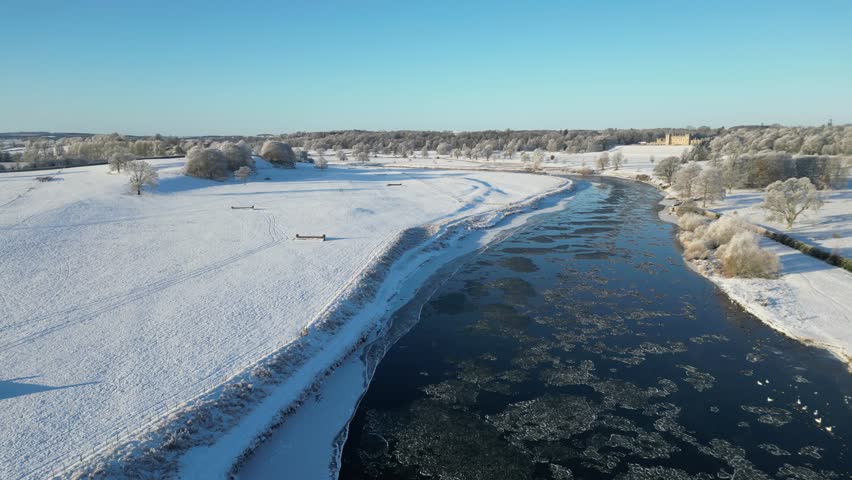 An aerial view of a river and a  forest in winter