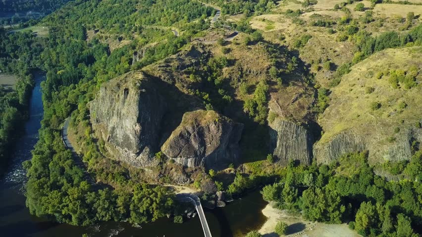 An aerial shot of the narrow river between the green rocks and mountains