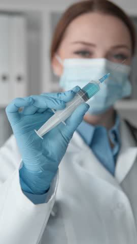 In a clinical setting, a healthcare professional is pictured holding a syringe for a vaccination procedure, ensuring the safety and protection of patients against diseases like COVID