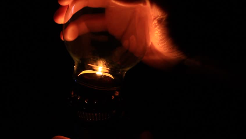 Man preparing an old fashioned lantern in darkness. How to light an oil lamp.
