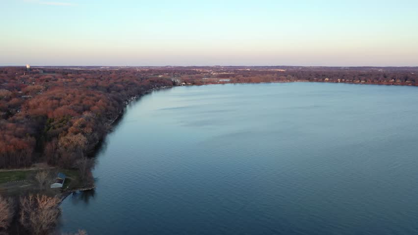 Aerial view of a lake in Madison, Wisconsin during sunset, with distant cityscape and serene water.