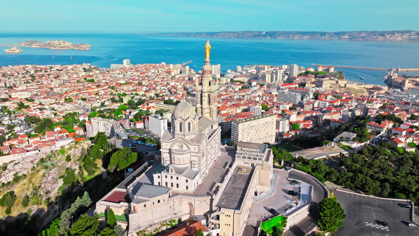 Grand basilica on top of a hill crowned by a golden statue, old city centre and port by blue Mediterranean sea coast in Marseille, France. Basilica of Notre Dame of la Garde at Marseille in France.