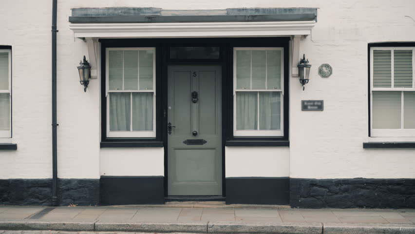 Gray entrance door of white house on street. Entrance to dwelling.