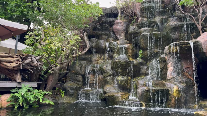 A wide shot of a waterfall that is replicated to decorate the garden in a coffee shop.