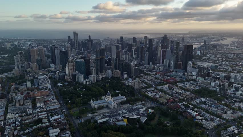 Skyline of Melbourne during dusk. Fitz Roy district with park area and Skyscrapers in Background. Yarra River behind high.rise Buildings at sunset. Aerial wide shot.