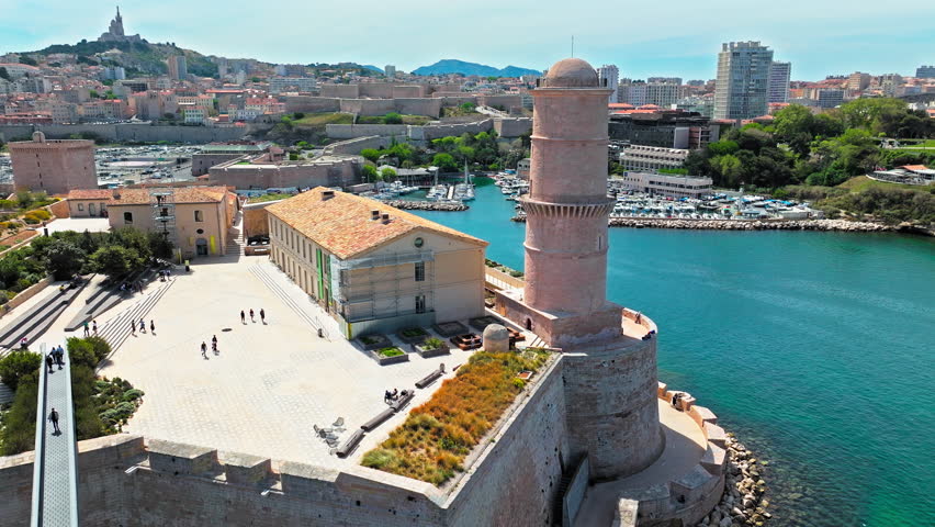 Aerial view of a fortress with a bridge leading to a regional history museum in Marseille, France. Scenic view of coastal area of Marseille overlooking medieval Fort Saint-Jean and Old Port.