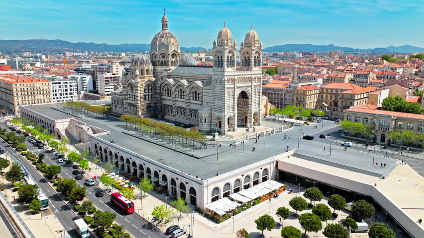 Aerial view of Byzantine cathedral with a striped facade, coloured stones, ornate domes and cupolas in Marseille. Cathédrale La Major features an opulent interior lined with murals and marble.
