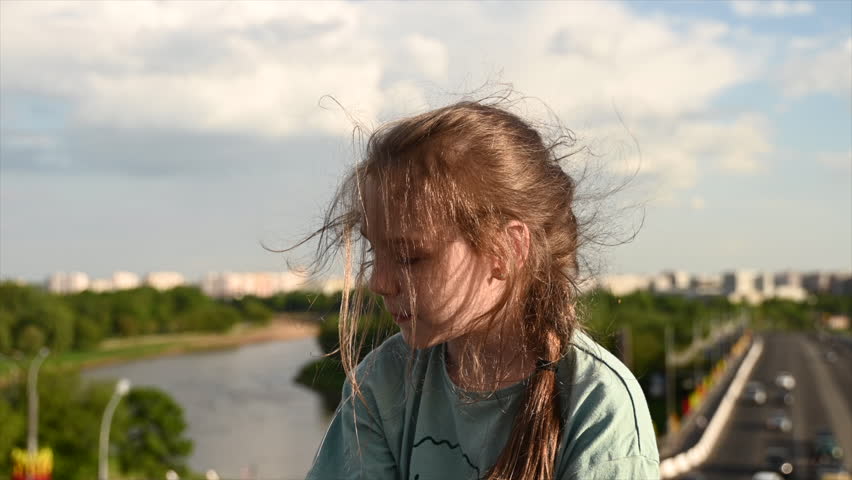 Girl against the backdrop of the city with hair flying in the wind