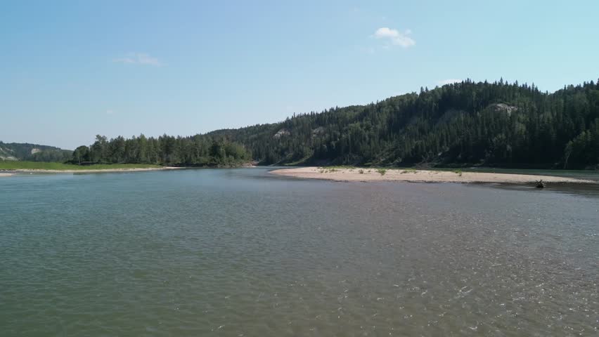 An aerial footage of a river surrounded by lush fir forest in North Saskatchewan