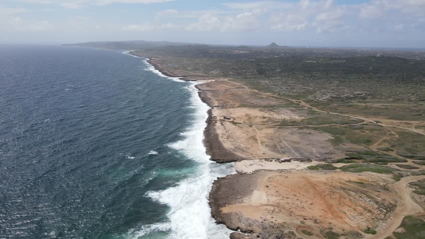 An aerial view of sea waves splashing on rocky coastline in Aruba