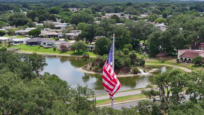 American flag waving in front of Florida neighborhood in The Villages, FL. Aerial parallax shot.